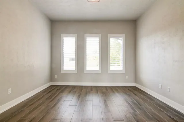 an empty room with wooden floor and windows