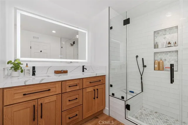 a bathroom with a granite countertop sink a mirror and a shower