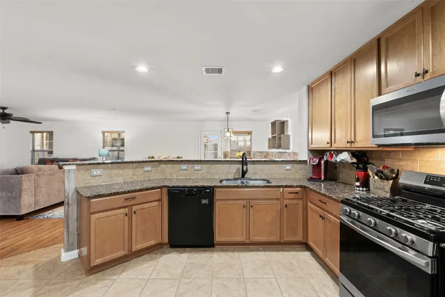 a kitchen with stainless steel appliances granite countertop a stove top oven a sink dishwasher and a refrigerator