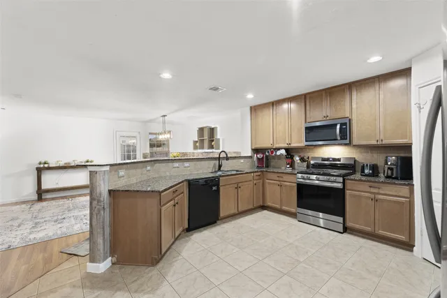 a kitchen with stainless steel appliances granite countertop a sink stove refrigerator and cabinets