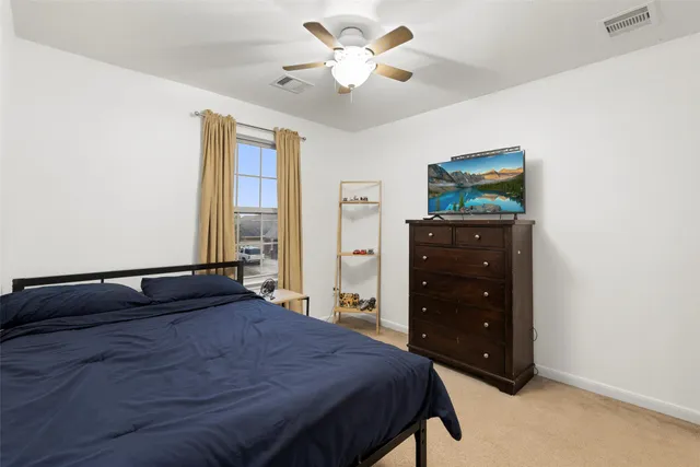 an empty room with a chandelier fan and windows