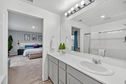 a spacious en suite bathroom with a double vanity sink and a mirror