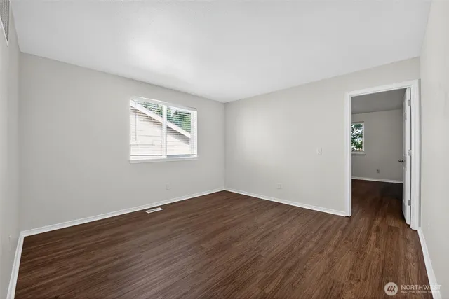 an empty room with wooden floor closet and windows