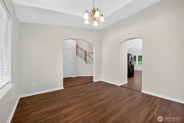 an empty room with wooden floor chandelier fan and windows