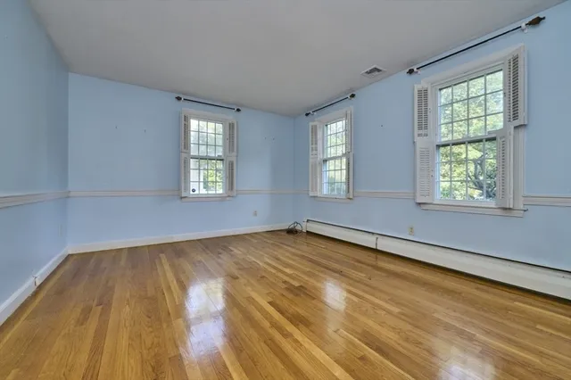 an empty room with wooden floor and windows