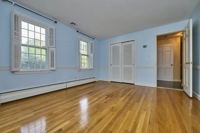 an empty room with wooden floor and windows