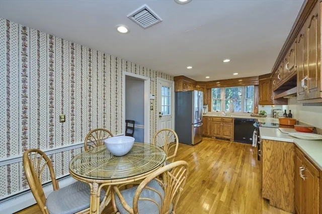 a kitchen with stainless steel appliances granite countertop a table chairs and a refrigerator
