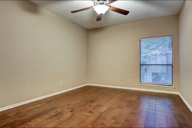 an empty room with windows and ceiling fan