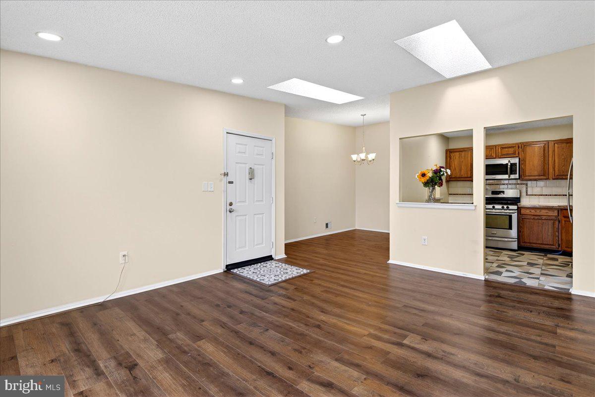 28 Holly Court Hamilton, NJ 08619 - Photo 11 of 29 an empty room with wooden floor and entrance to kitchen