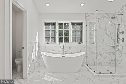 a spacious bathroom with a tub sink and mirror