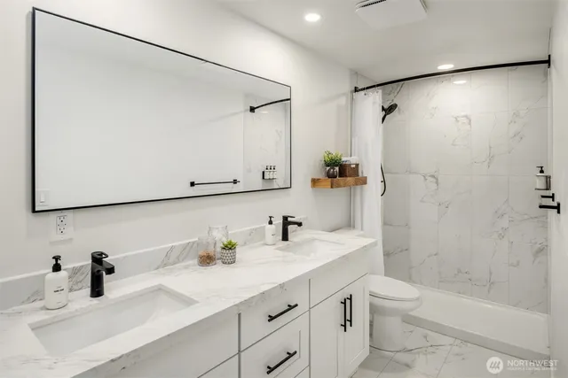 a bathroom with a sink toilet double vanity and shower