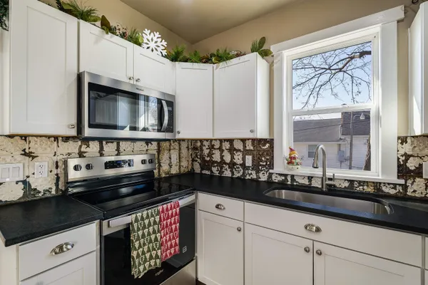 a kitchen with granite countertop a sink stove and microwave