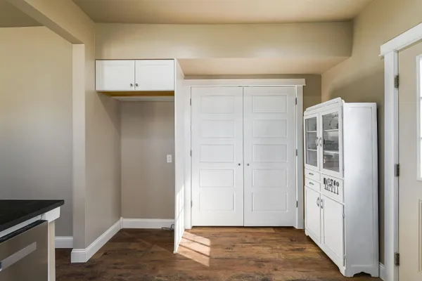 a view of an empty room with closet and wooden floor