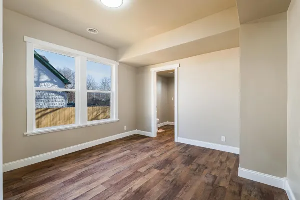 an empty room with wooden floor and windows