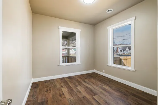 an empty room with wooden floor and windows