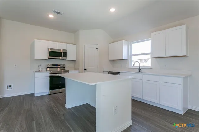 a kitchen with cabinets stainless steel appliances a sink and wooden floor
