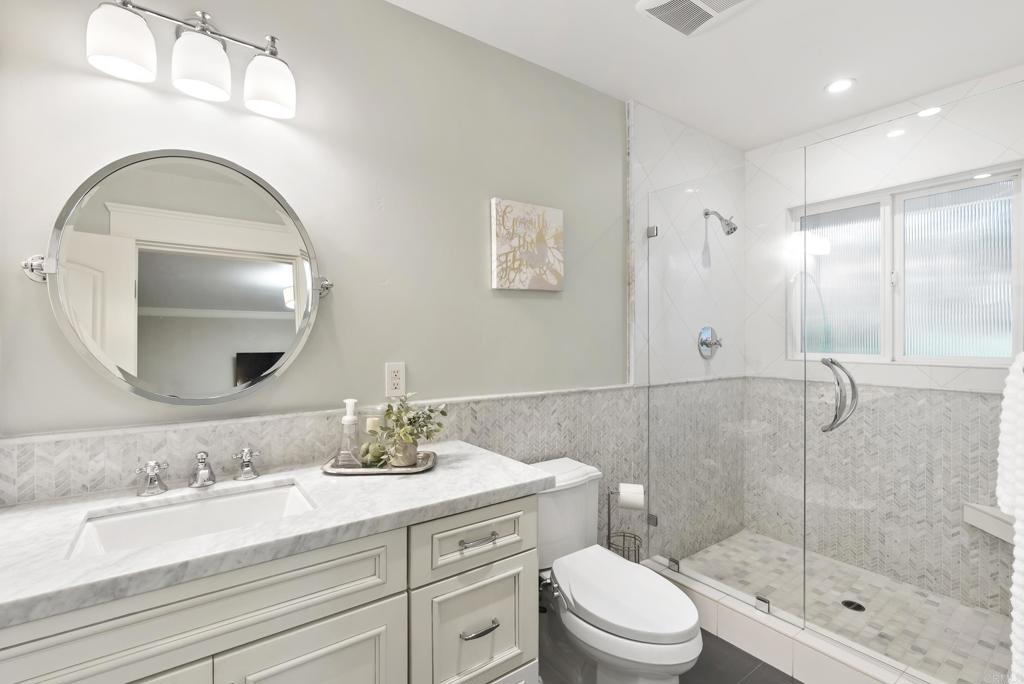 4847 Vita Road La Mesa, CA 91941 - Photo 41 of 73 a bathroom with a toilet a sink a glass door shower and mirror