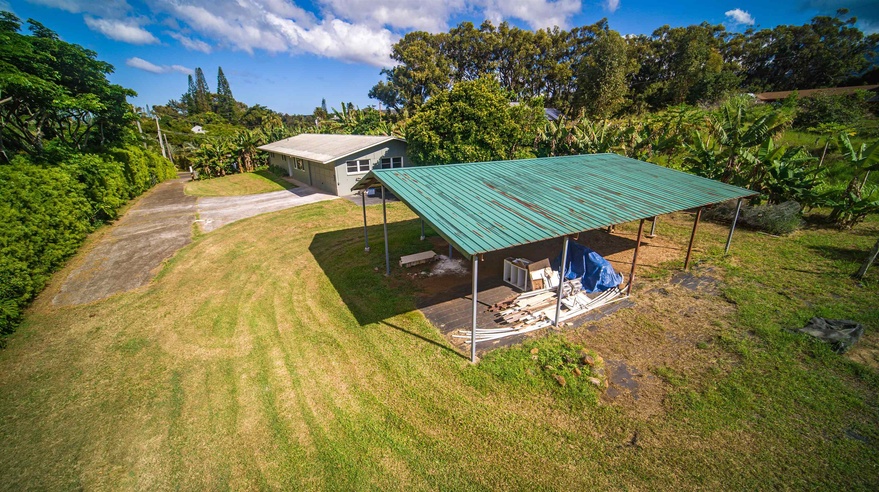 1660 West Kuiaha Road, Unit A Haiku, HI 96708 - Photo 26 of 30 a view of a patio with table and chairs under an umbrella next to a yard