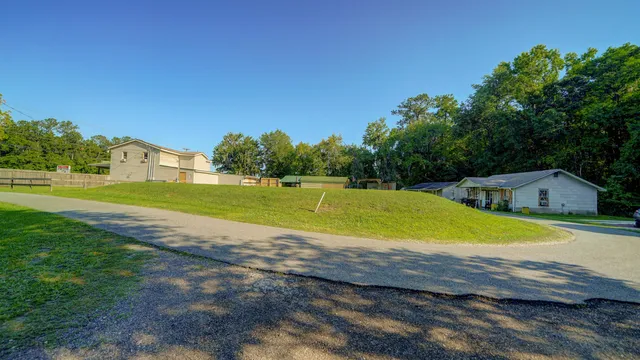 a view of a swimming pool with a yard and a large tree