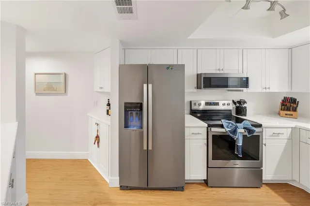 a kitchen with stainless steel appliances white cabinets and a refrigerator