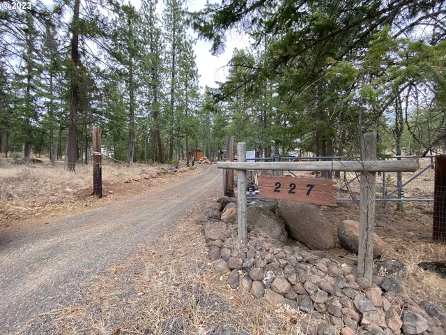 a backyard of a house with large trees and covered with wooden fence