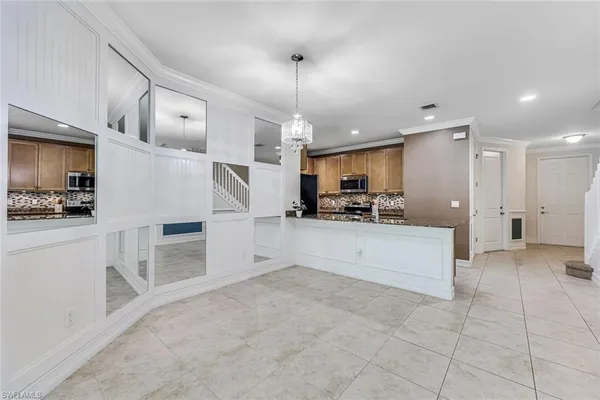 a large white kitchen with stainless steel appliances kitchen island granite countertop a refrigerator and microwave