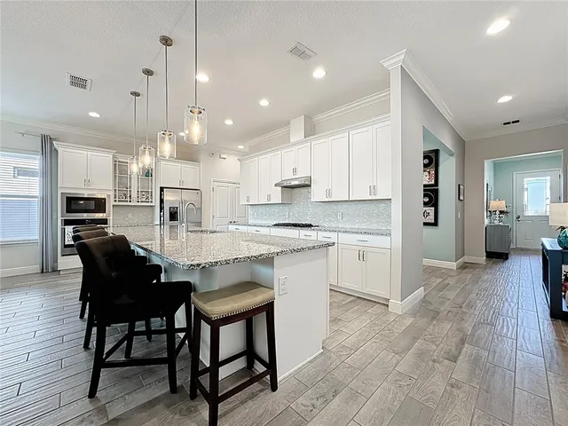 a large kitchen with kitchen island a dining table chairs and white cabinets