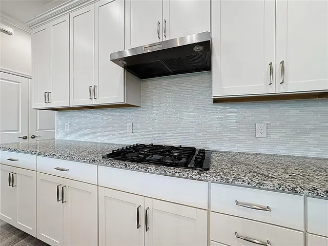 a kitchen with granite countertop a sink a counter top space appliances and cabinets