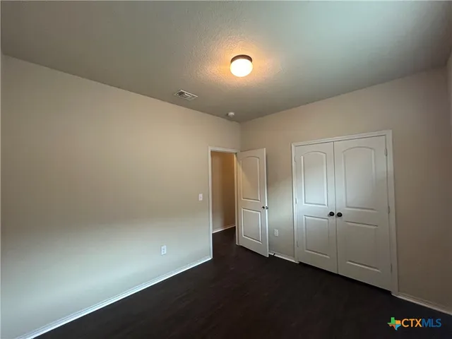 an empty room with wooden floor and closet