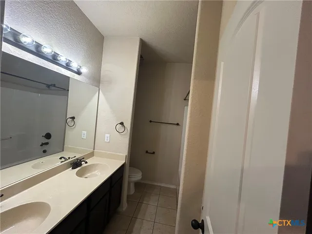 a bathroom with a double vanity sink a toilet and a mirror