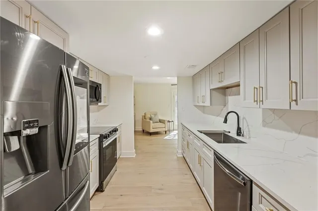a kitchen with stainless steel appliances granite countertop a sink dishwasher a stove and white cabinets with wooden floor