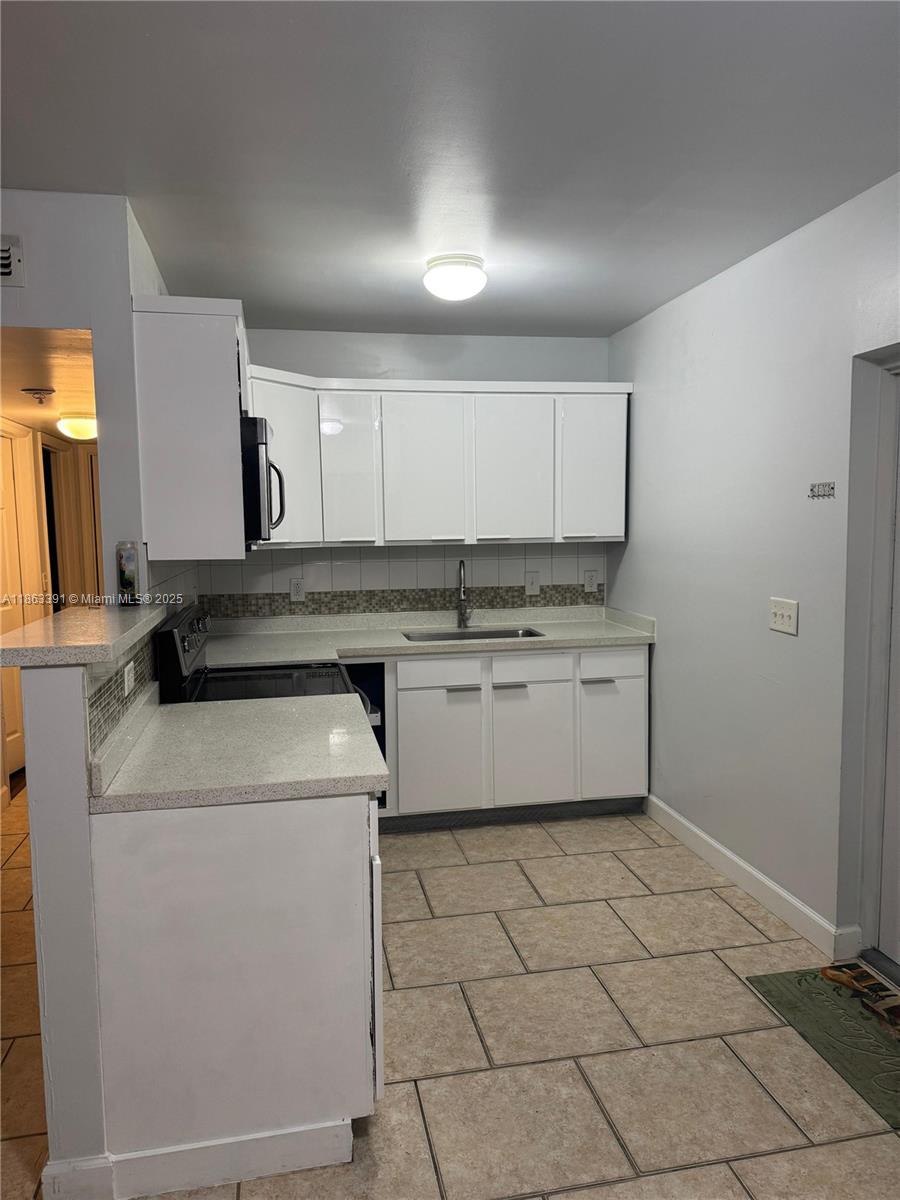 4351 Northeast 18th Avenue Pompano Beach, FL 33064 - Photo 4 of 18 a kitchen with a stove top oven and cabinets