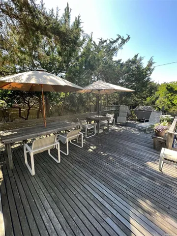 a view of a patio with table and chairs under an umbrella with wooden floor