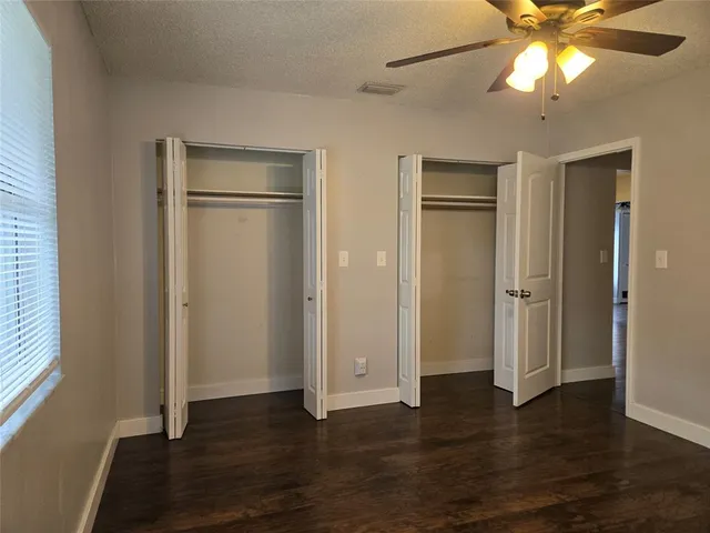 an empty room with wooden floor closet and windows