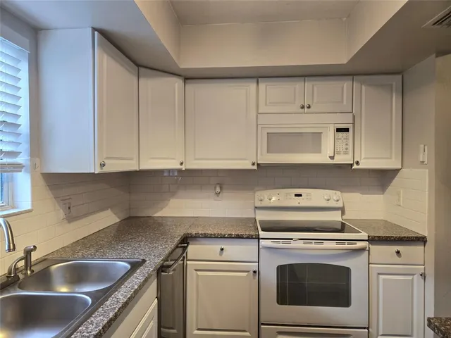 a kitchen with white cabinets sink and stove
