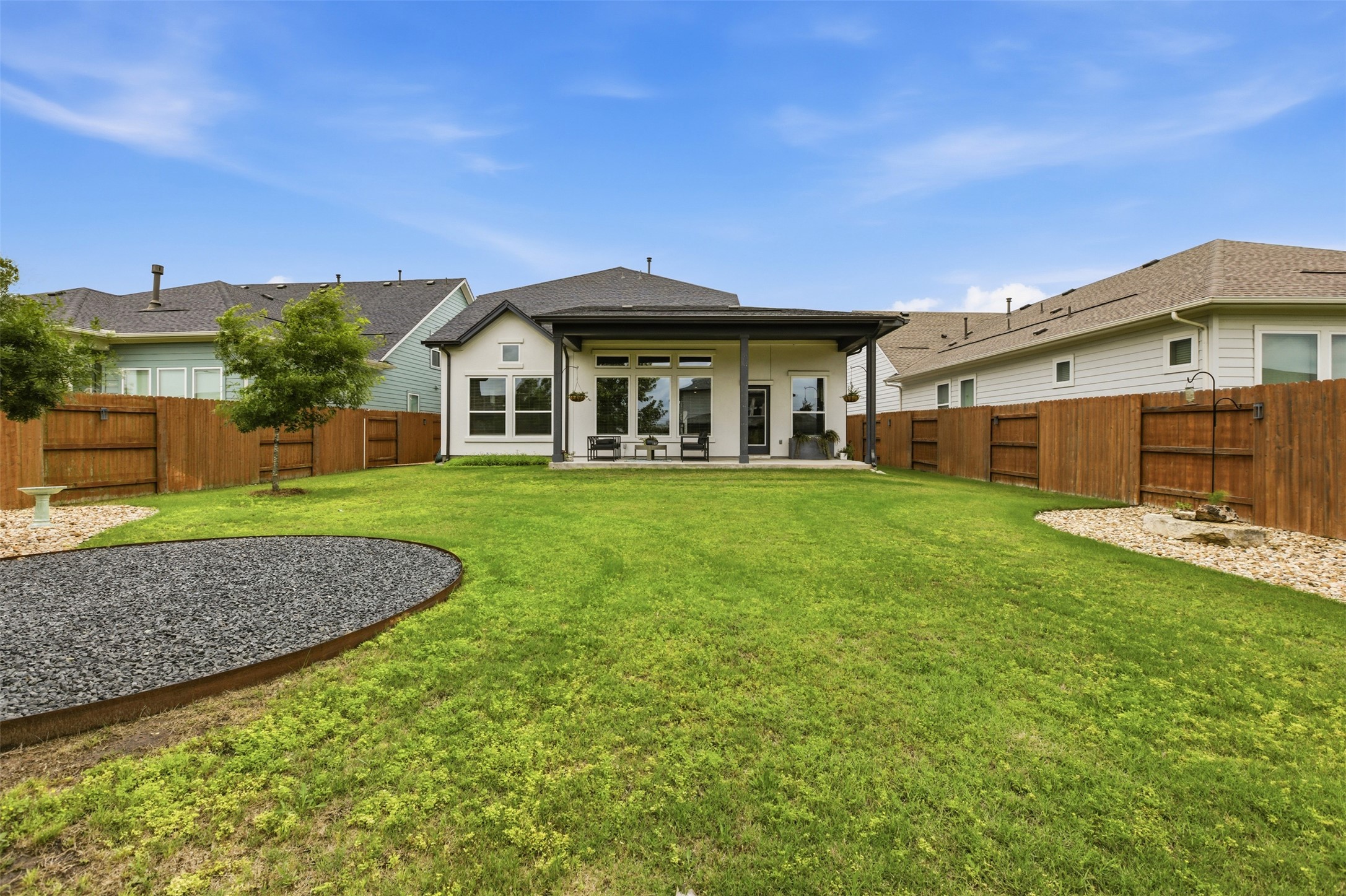 9001 Spire View Austin, TX 78744 - Photo 34 of 35 Expansive backyard featuring a large green lawn, full wood privacy fencing, and a covered patio with recessed lighting