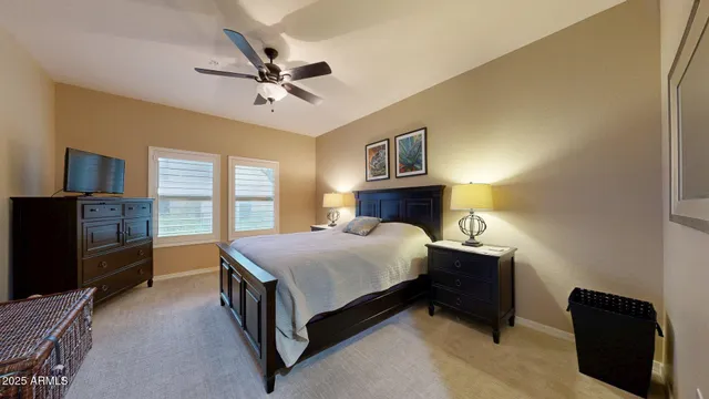 a spacious bedroom with a bed and a flat tv screen on dresser