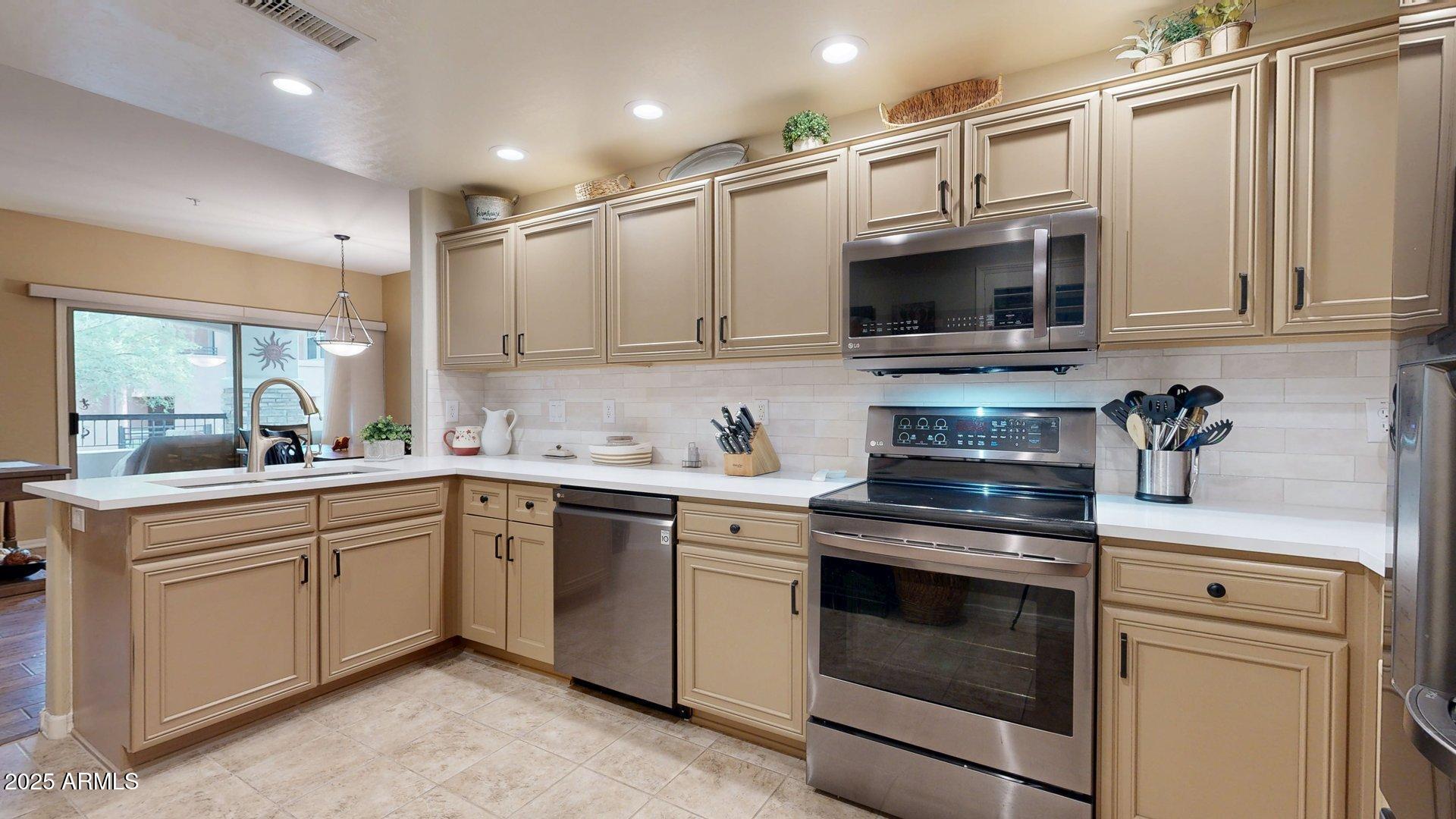 20121 North 76th Street, Unit 1047 Scottsdale, AZ 85255 - Photo 9 of 22 a kitchen with stainless steel appliances granite countertop a stove sink microwave and cabinets