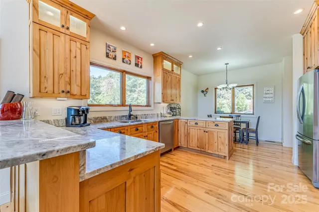 a kitchen with stainless steel appliances granite countertop wooden cabinets a dining table and chairs