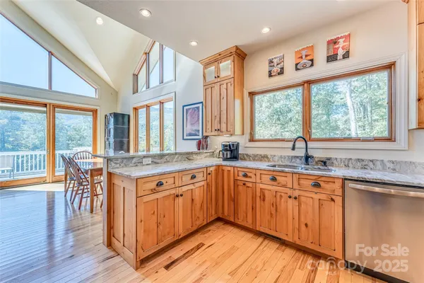 a kitchen with stainless steel appliances granite countertop a stove a sink dishwasher and a large refrigerator with wooden floor