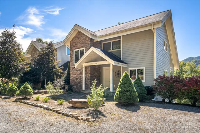 a view of a white house next to a yard with potted plants