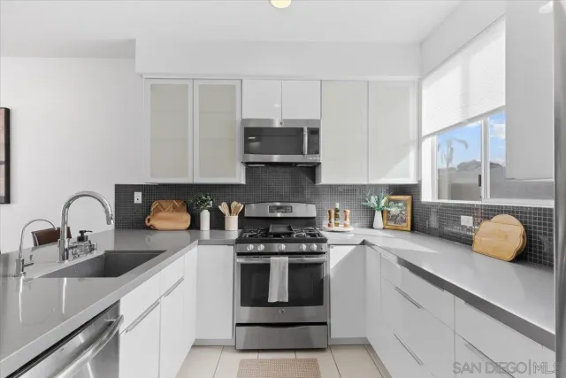 a kitchen with granite countertop a stove a sink and wooden cabinets