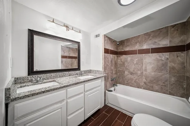 a bathroom with a granite countertop sink mirror vanity and bathtub