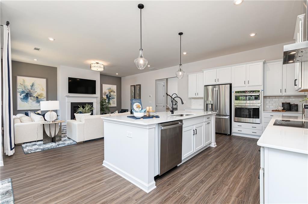 752 Coventry Cv Way Acworth, GA 30102 - Photo 15 of 34 a kitchen with stainless steel appliances kitchen island granite countertop a stove top oven a sink dishwasher a refrigerator and white cabinets with wooden floor