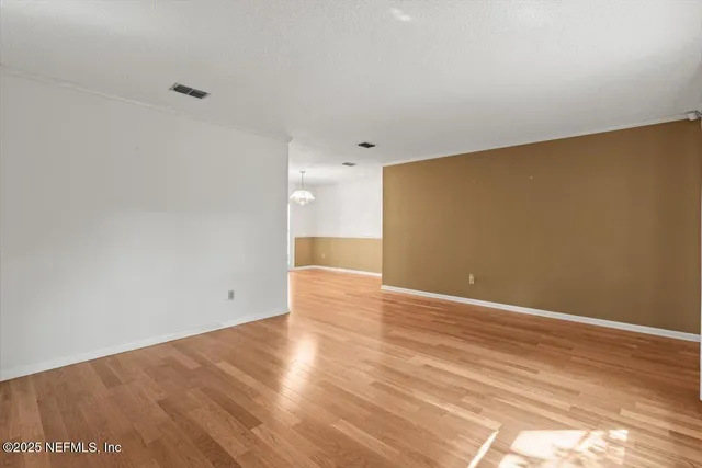 a view of an empty room with window and wooden floor