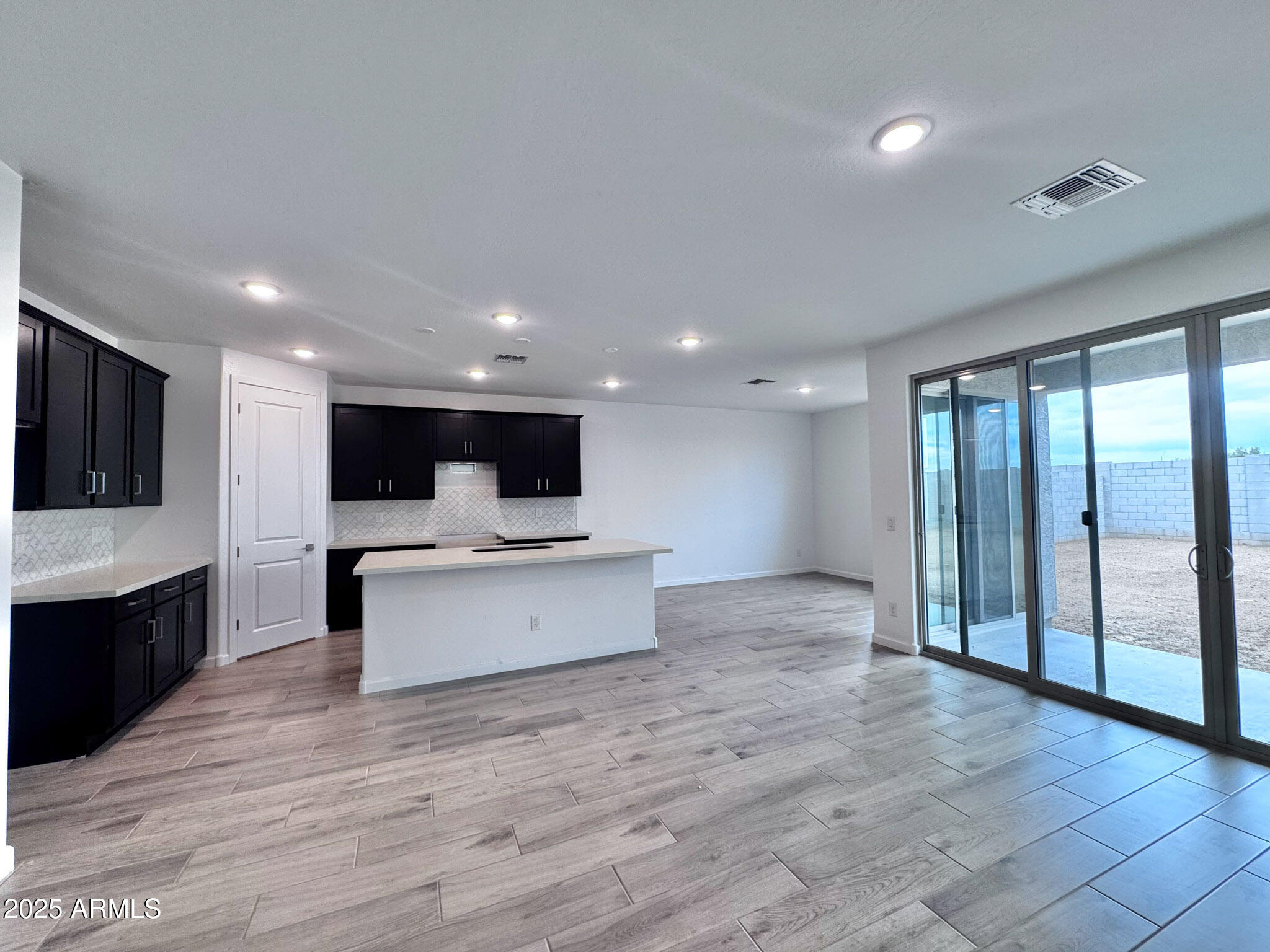 15740 West Camden Avenue Waddell, AZ 85355 - Photo 11 of 38 a view of living room with kitchen island stainless steel appliances wooden floor and window
