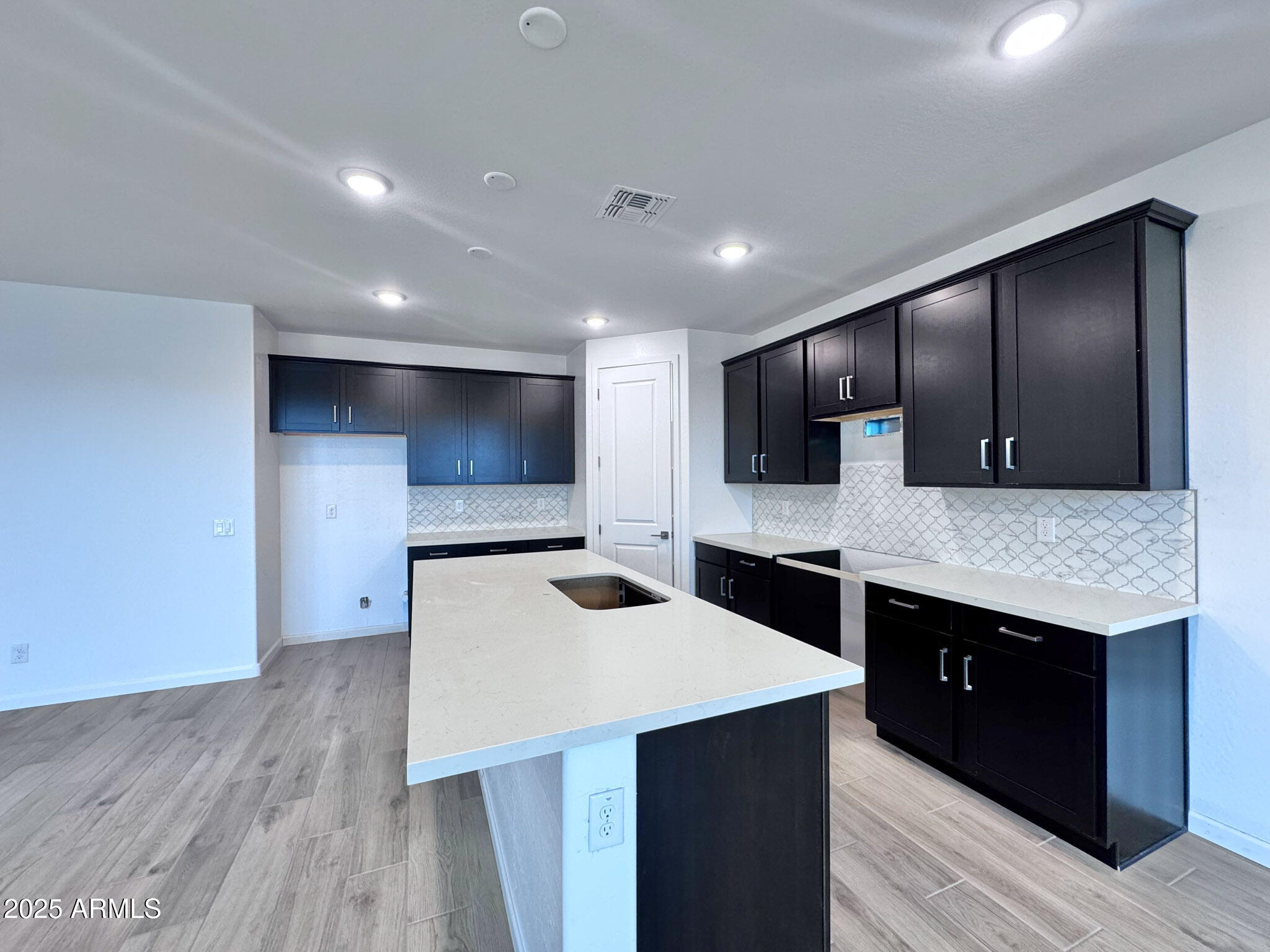 15740 West Camden Avenue Waddell, AZ 85355 - Photo 13 of 38 a kitchen with stainless steel appliances kitchen island a cabinets and wooden floor