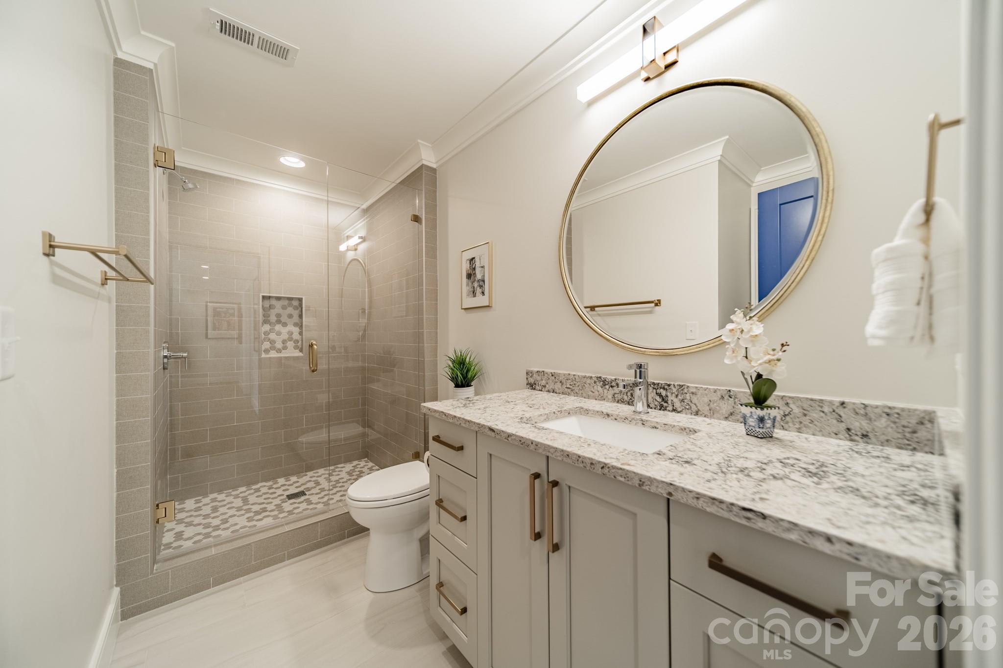 5400 Colony Road Charlotte, NC 28226 - Photo 21 of 48 a bathroom with a granite countertop sink a toilet a mirror and shower