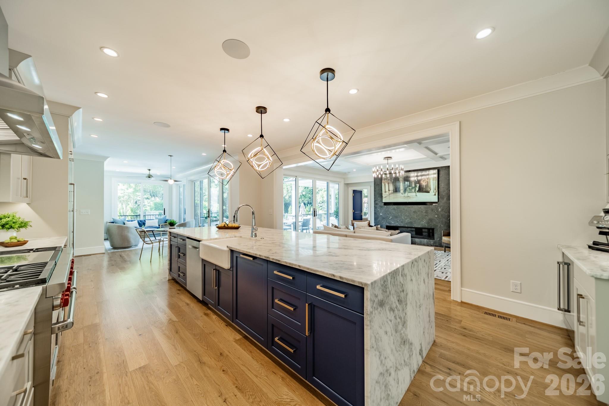 5400 Colony Road Charlotte, NC 28226 - Photo 7 of 48 a large kitchen with kitchen island a stove a sink a chimney and a dining table with wooden floor