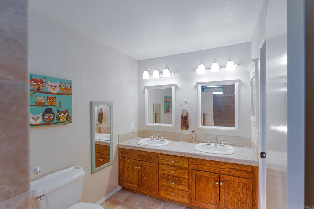 1921 Via Corina Alpine, CA 91901 - Photo 34 of 62 a bathroom with a granite countertop sink a toilet a mirror and a bathtub